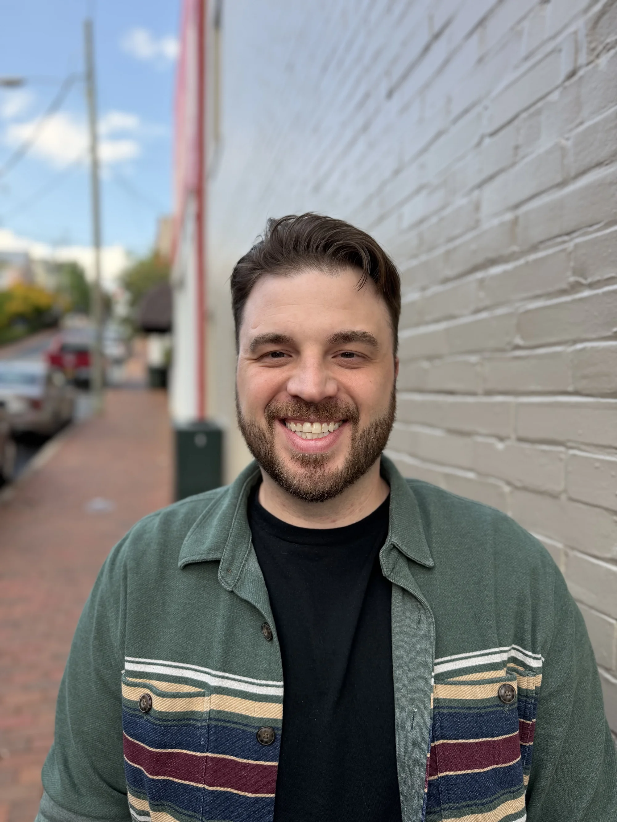 Portrait of Zack Baker, Roamler's Head of Sales, smiling outside a brick building